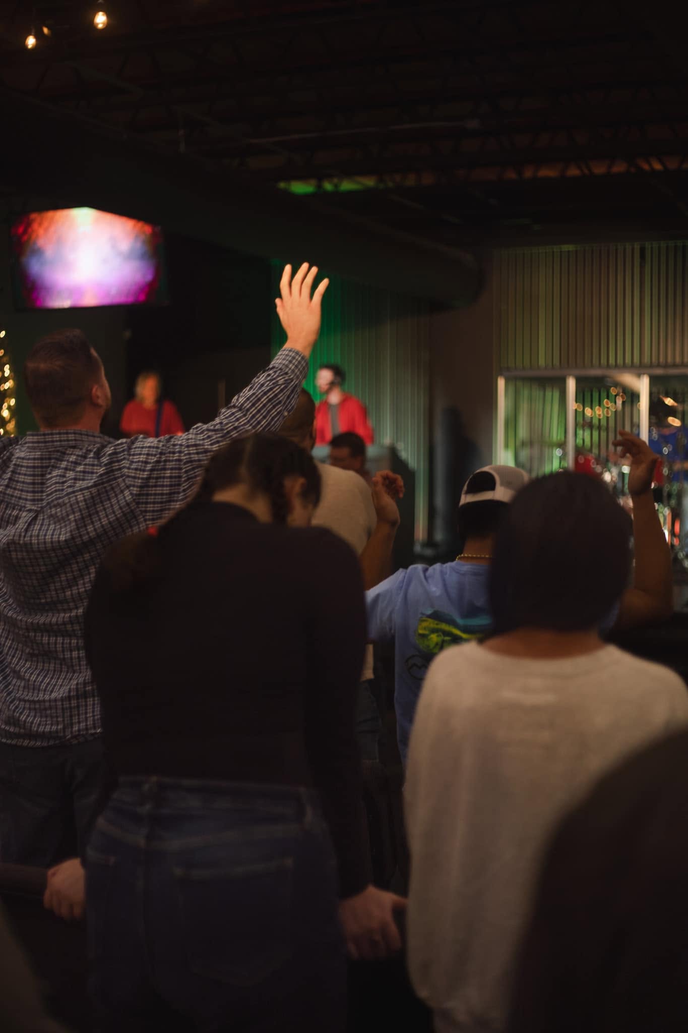 A worshiper with hand raised during a Sunday service at Hope House Church
